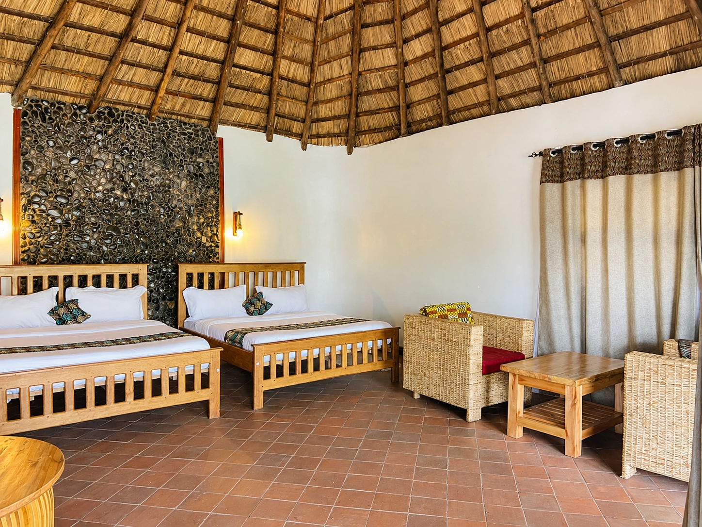 Two king size beds arranged beneath the double cottage thatched roof at Bahundu near Fort Portal, Uganda