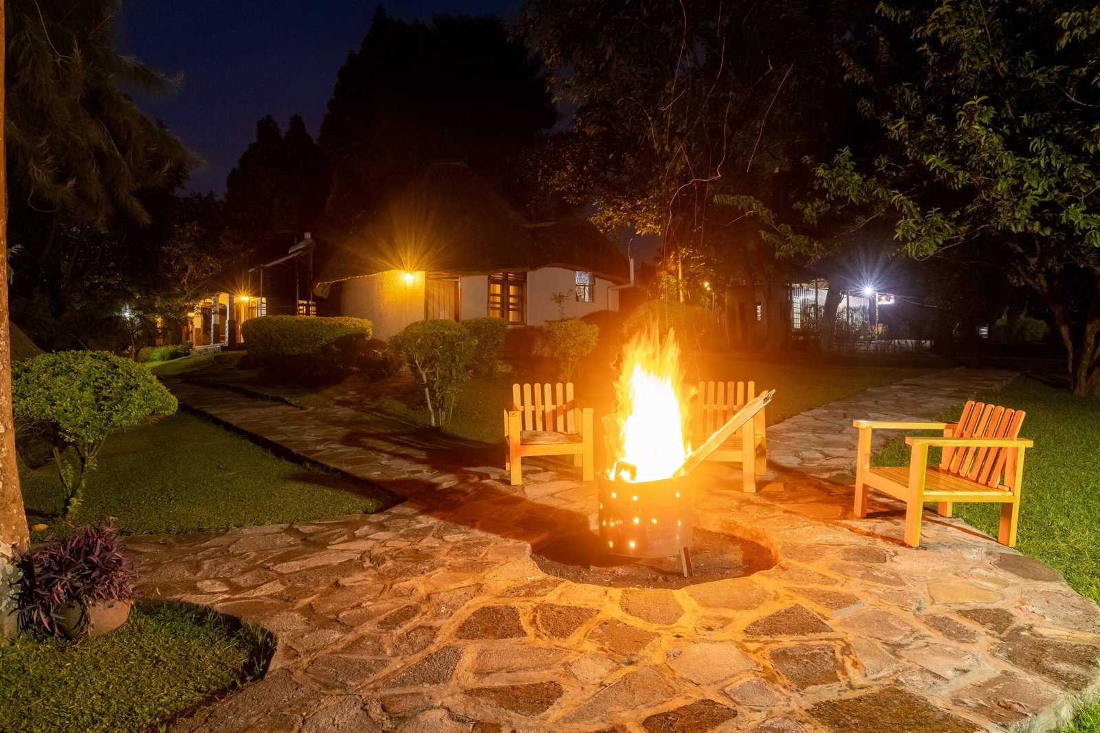 An open fire burning in the garden firepit with chairs drawn around it at night
