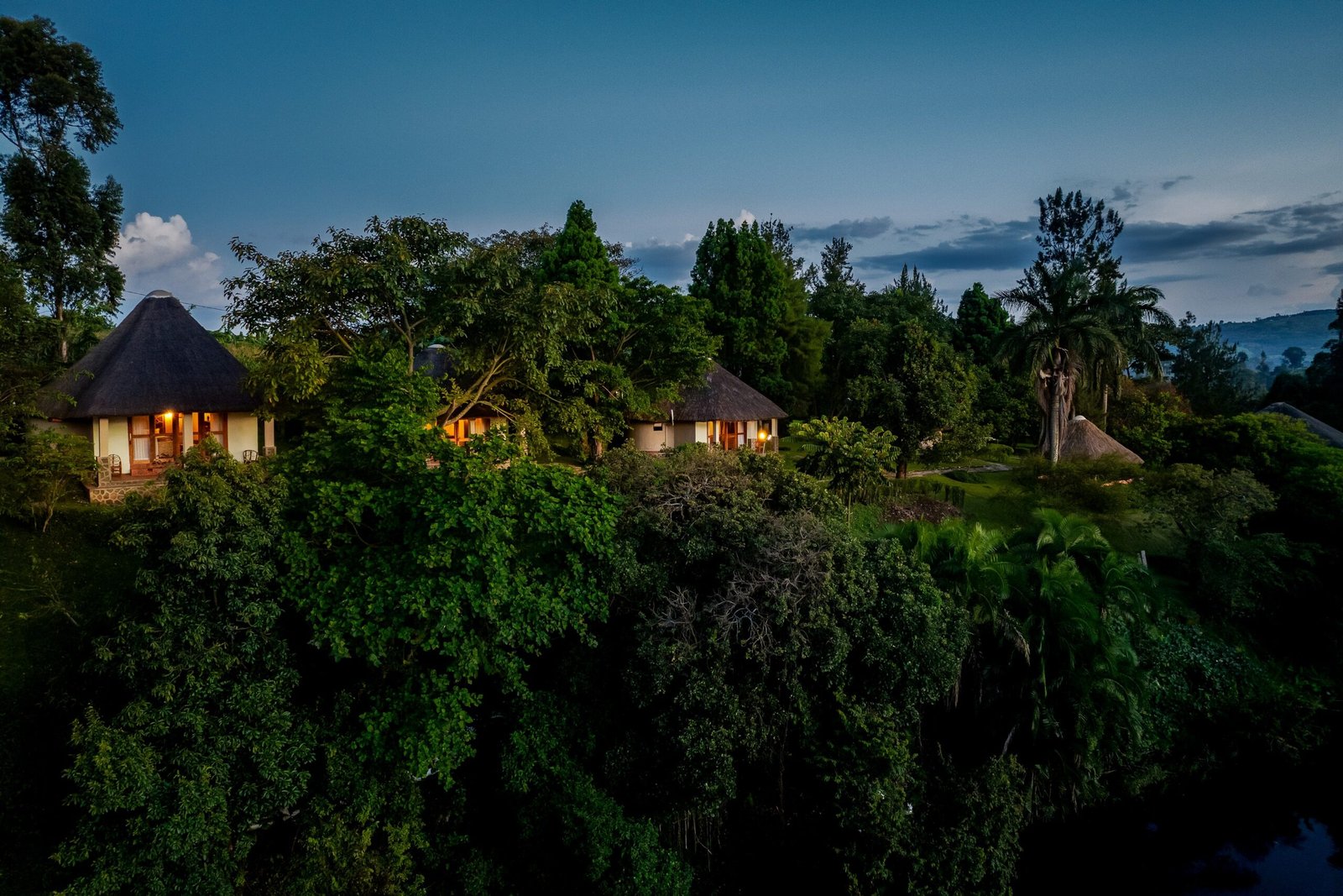 Bahundu cottages glowing at dusk beside Lake Nyinabulitwa
