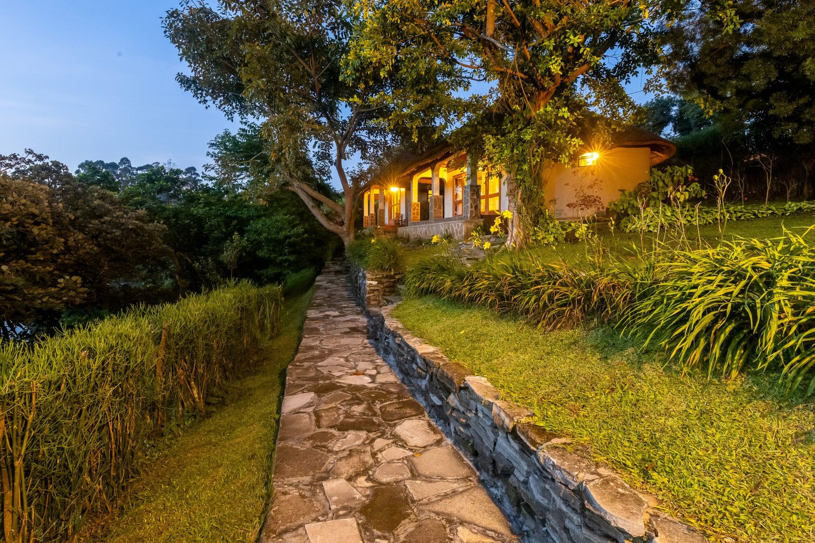A stone path lit between the cottages under a deep blue evening sky