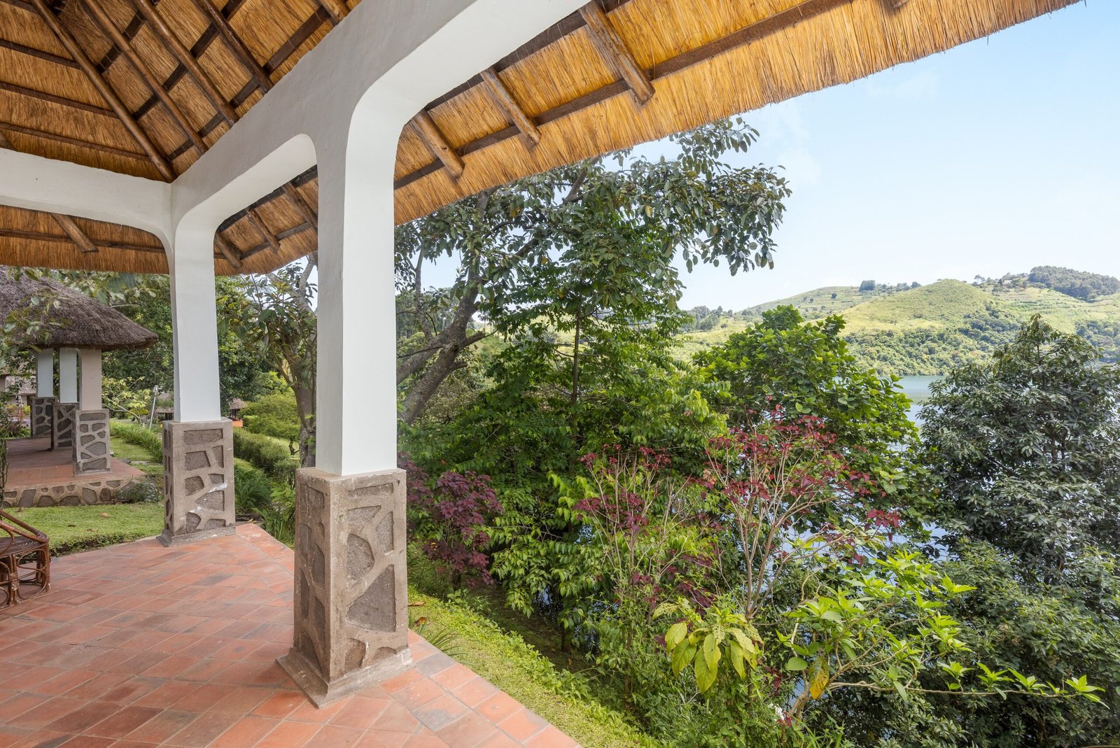 Twin beds under the thatched roof of a double cottage, with glass doors opening onto the crater lake at Bahundu near Fort Portal, Uganda