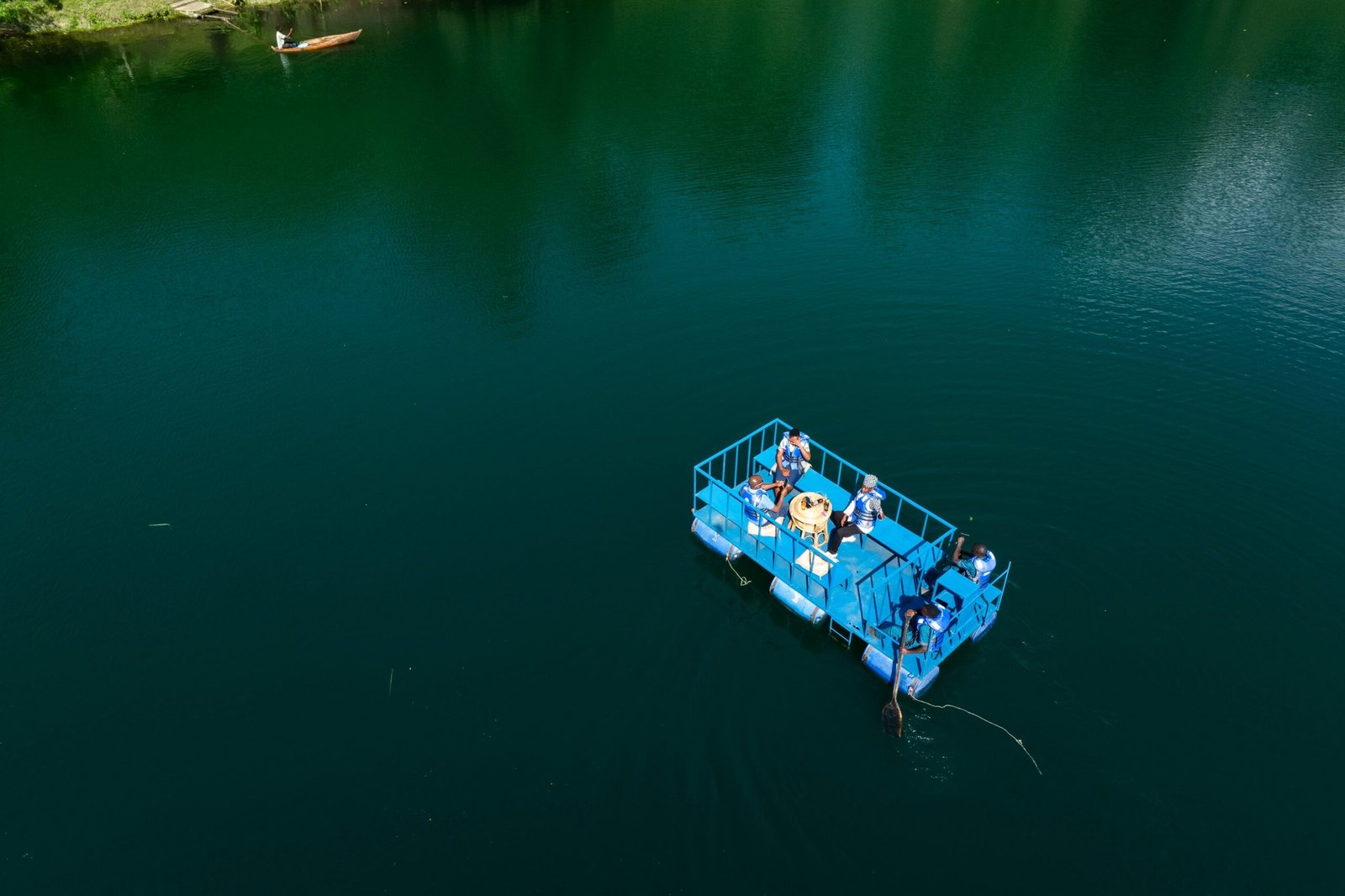A small boat crossing the deep green water of Lake Nyinabulitwa, seen from above