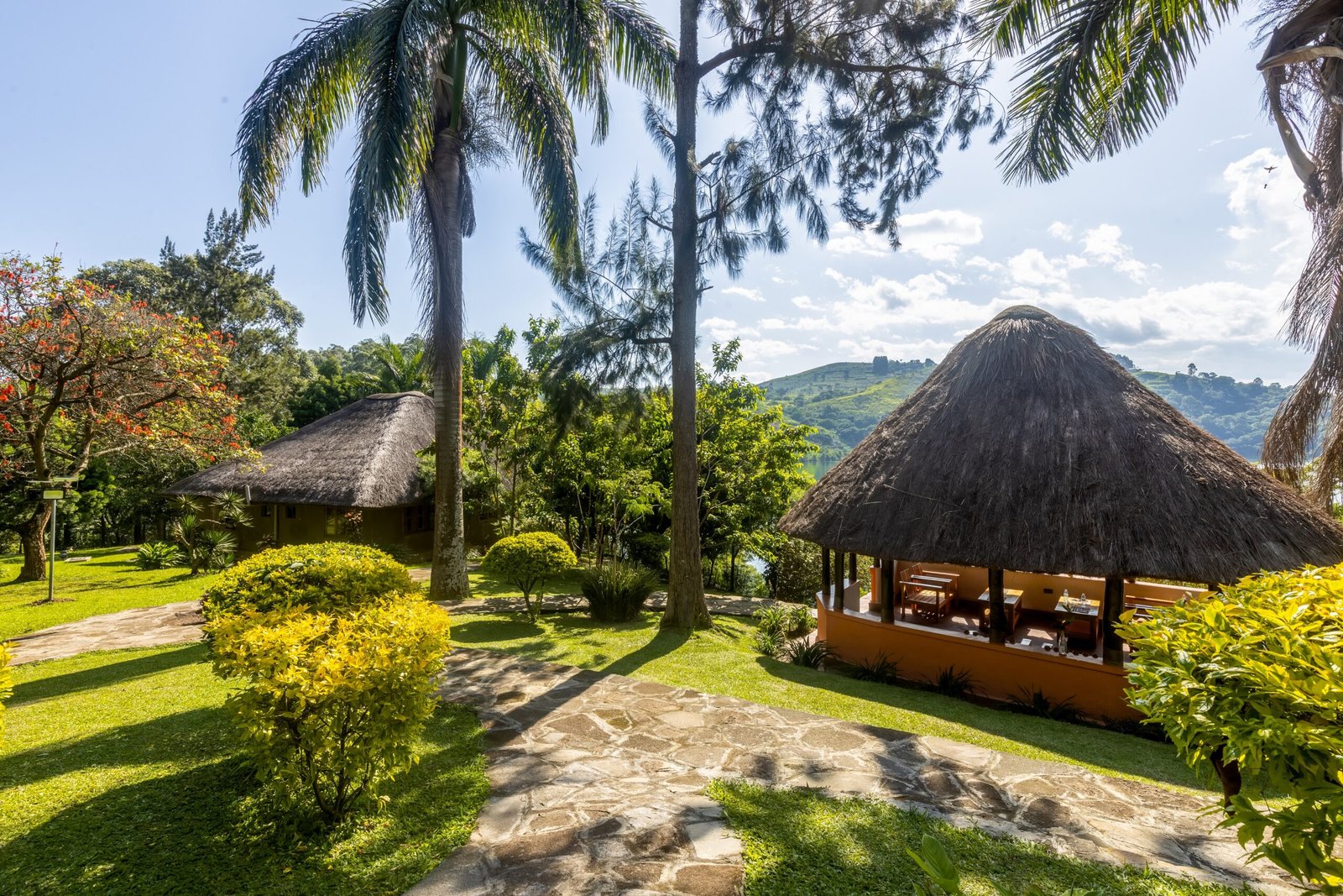 Tall palms and a stone path leading to a thatched pavilion in the lodge gardens