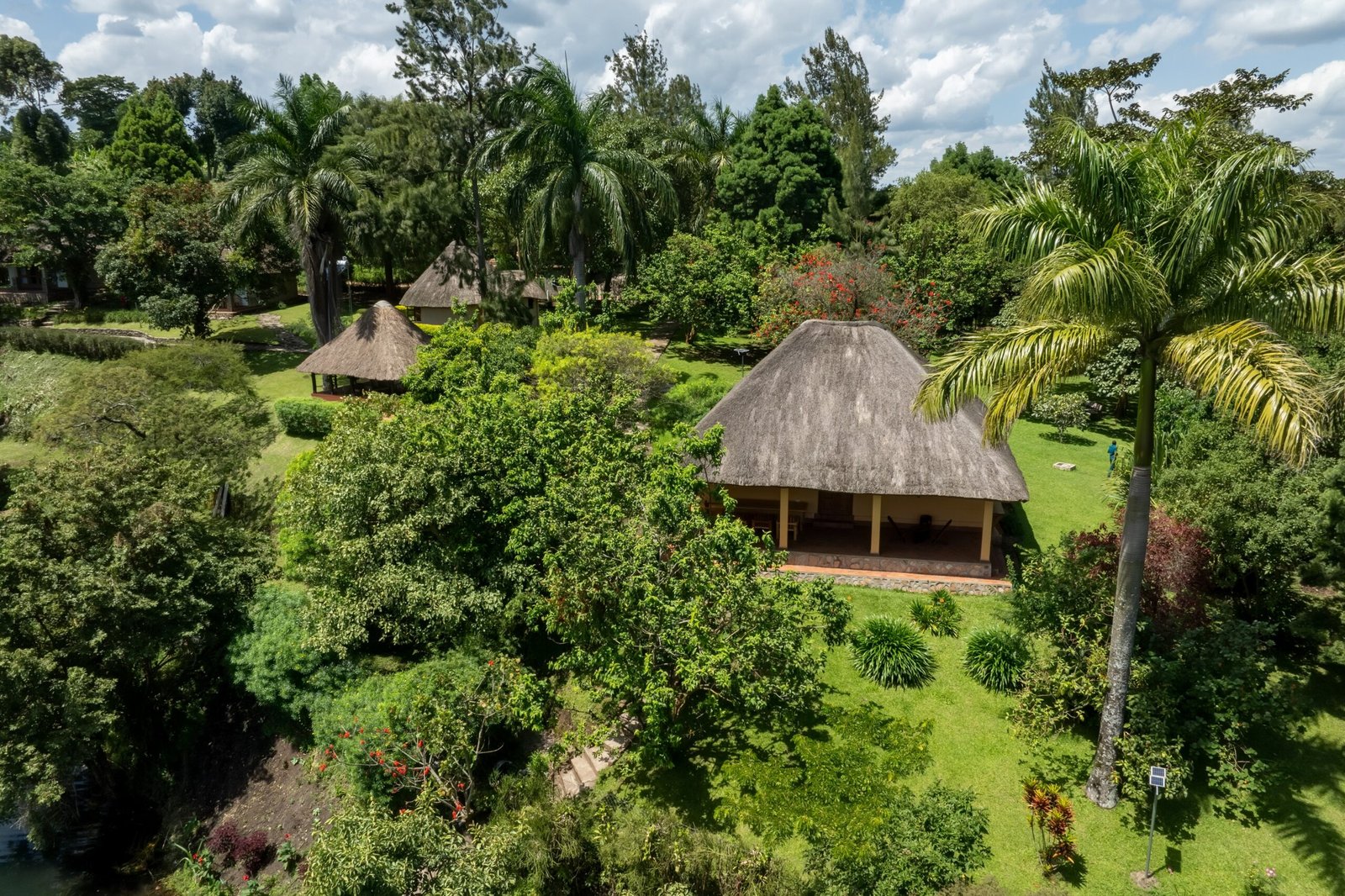 Thatched cottages spaced quietly through the gardens above the crater lake at a secluded East African retreat near Fort Portal