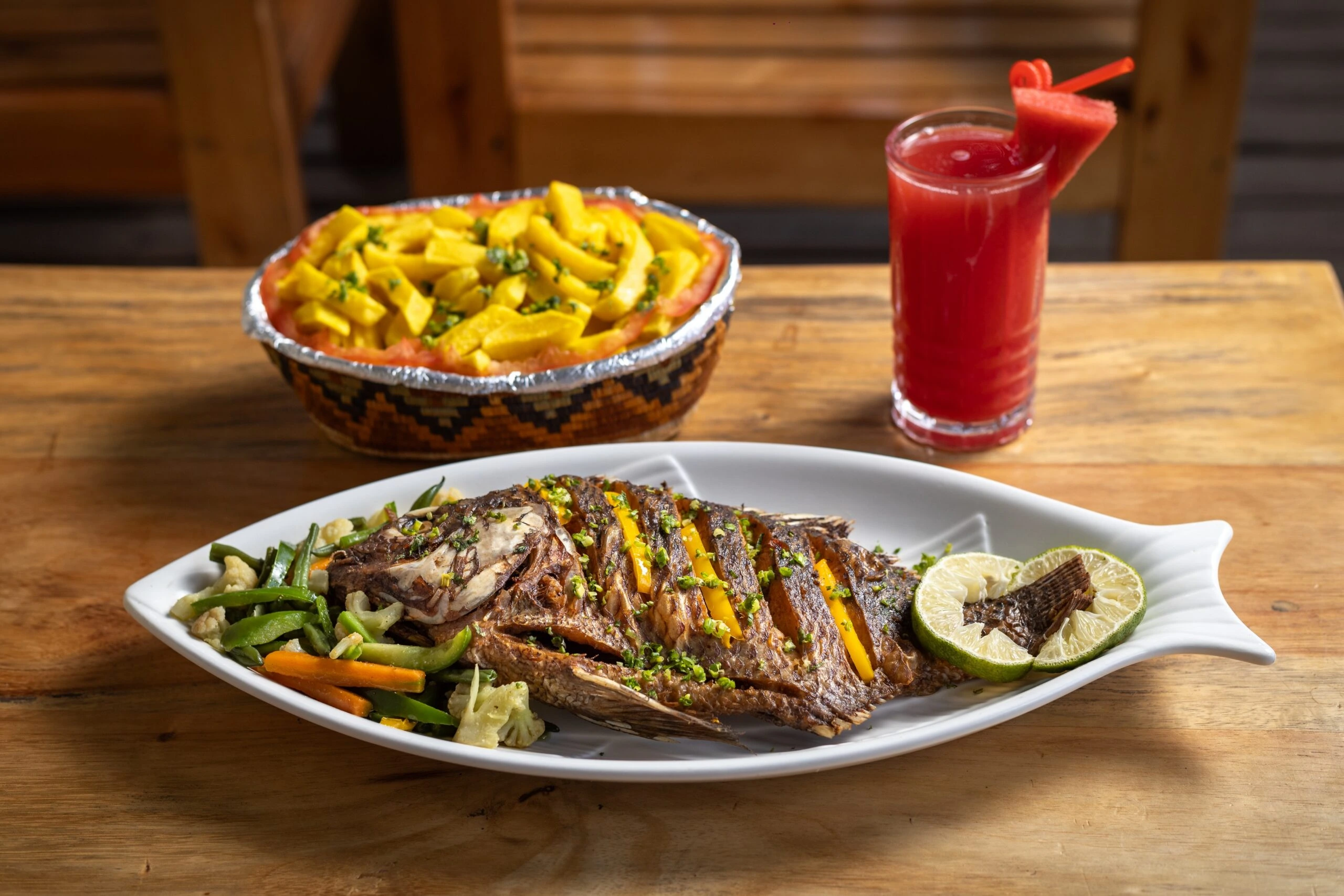 Mouth watering whole tilapia served with colourful local sides at the Fort Portal crater lake retreat in Uganda